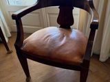 a wooden chair with a leather seat in front of a window