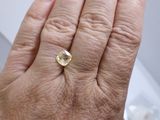 a person ' s hand holding a ring with a yellow stone