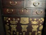 a wooden chest of drawers with gold decorations on it