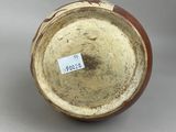 a brown and white vase with a label on it