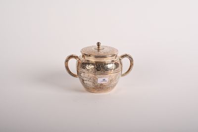 une théière ancienne en argent avec son couvercle, posée sur une surface blanche