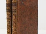 two old books sitting on top of each other on a white surface