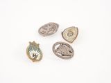 trois épingles ornées de motifs différents, posées sur une surface blanche