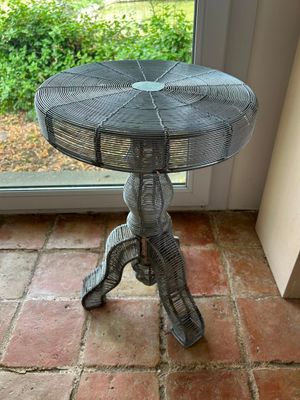 a small table with a fan on it in front of a window