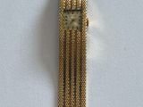 un bracelet en or orné d'une montre, posé sur un fond blanc
