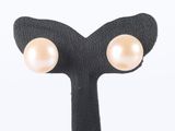 pair of pearl earrings on a black stand against a white background