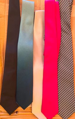 quatre cravates de couleurs différentes disposées sur une surface en bois