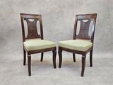 two wooden chairs with green upholstered seats against a white backdrop