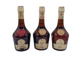 three bottles of liquor sitting next to each other on a white surface