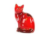 une figurine de chat rouge posée sur une surface blanche
