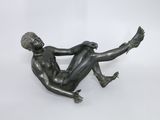 statue en bronze représentant un homme allongé sur le dos sur un fond blanc
