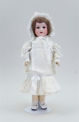 une poupée ancienne en porcelaine représentant une femme vêtue d'une robe blanche et d'un bonnet