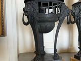 two black vases sitting on a table with a cat on top of them