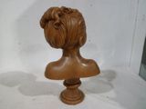 un petit buste en bois représentant une femme, posé sur une table