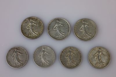 six types différents de pièces d'argent sur une surface blanche