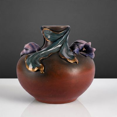 un vase marron avec des fleurs violettes posé sur une table