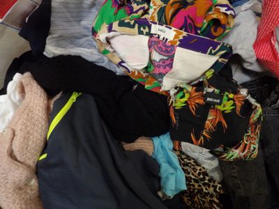 a pile of clothes and a teddy bear in a suitcase