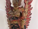 wooden statue of a person holding a bird on a white surface