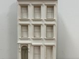 doll house on a wooden table with a white wall behind it
