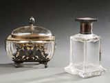 une paire de flacons de parfum en argent et en verre, munis de couvercles, posés sur un support gris