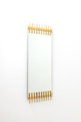miroir rectangulaire fixé à l'aide de chevilles en bois sur un mur blanc