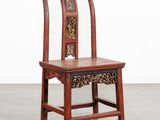une chaise en bois dont le dossier et l'assise sont sculptés, dans une pièce