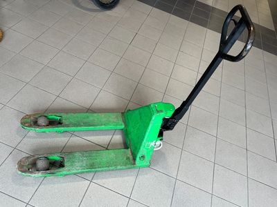 un chariot élévateur vert posé par terre dans une pièce