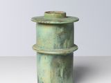 un gros plan d'un vase vert posé sur une surface blanche