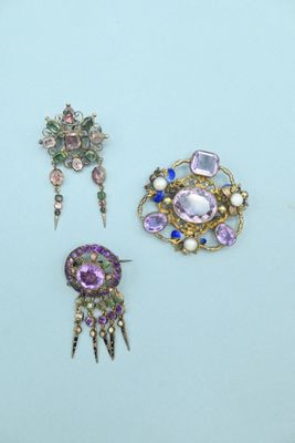 three pieces of jewelry on a table with a blue background