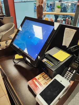 a desk with a monitor, keyboard, phone, and other items on it