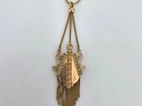 a gold necklace with fringes and a pendant with a bird on it