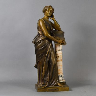 an antique bronze statue of a woman holding a vase
