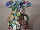 a glass vase with a multicolored design sitting on a table