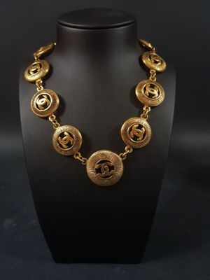 un collier en or sur un mannequin d'exposition, sur fond noir