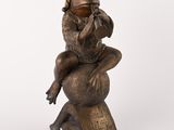 bronze statue of a woman sitting on a globe with a monkey on her back