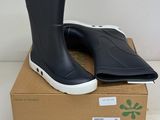 des bottes de pluie noires à semelles blanches posées sur une boîte en carton