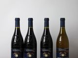 quatre bouteilles de vin sont alignées sur une table en bois