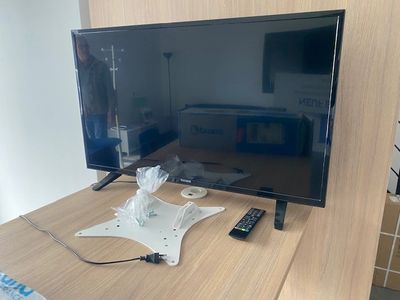 a flat screen tv sitting on a desk with a remote control