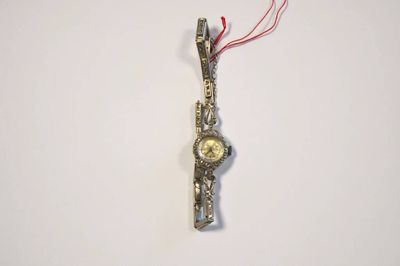 une montre en argent à laquelle est accroché un cordon rouge sur le côté