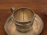 une tasse et une soucoupe en argent posées sur une table en bois