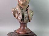 bronze bust of a man with a scarf on a wooden base