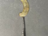 a silver spoon with a gold crescent on it