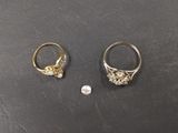 two gold rings and a small diamond on a black surface