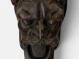 an image of a wooden mask mounted on the side of a wall
