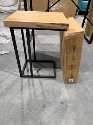 La table est en bois et possède un piètement en métal.