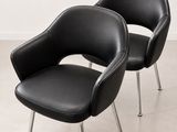 une paire de fauteuils en cuir noir aux pieds chromés dans une pièce blanche