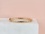 a close up of a gold bang bracelet on a marble block