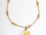 a gold necklace with a coin on a chain