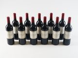 six bottles of red wine lined up in a row on a white surface