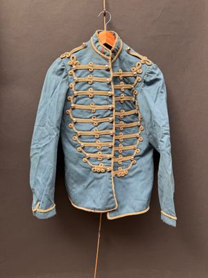 une vieille veste militaire bleue suspendue à un cintre accroché au mur